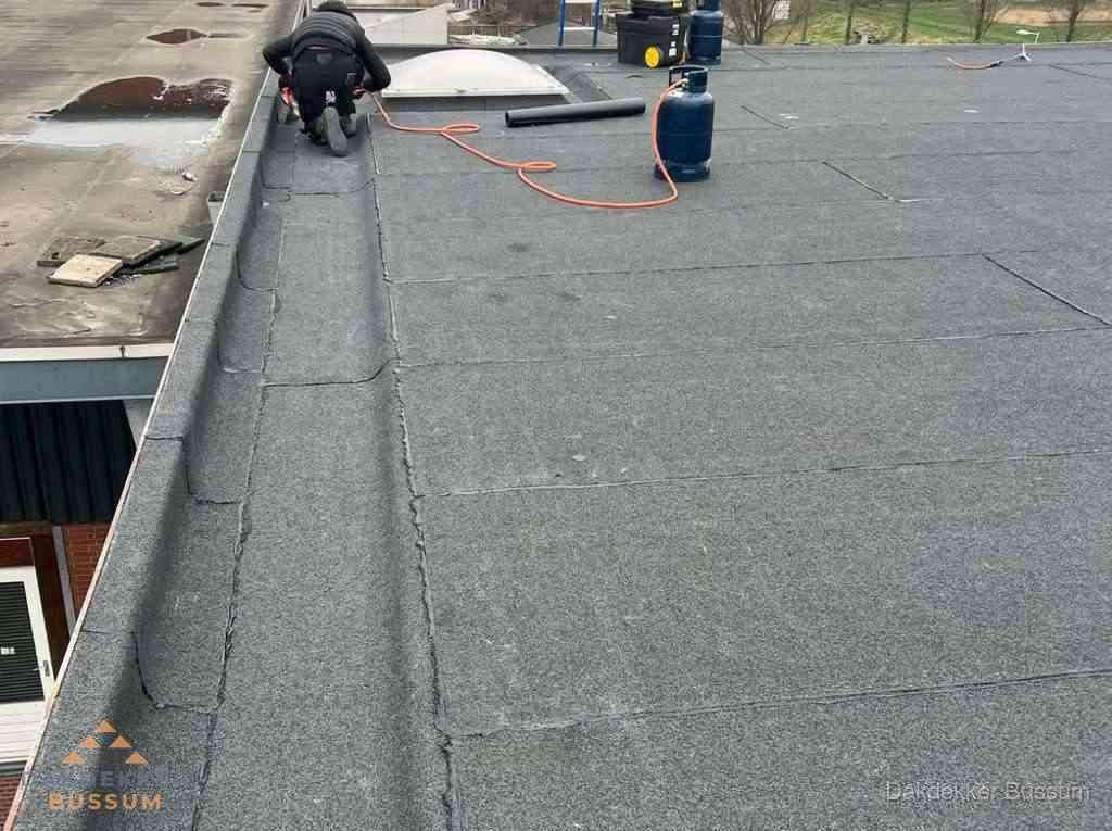 Dakdekker repareert bitumen dakbedekking op groot plat dak in Bussum Dakdekker repareert bitumen dakbedekking op groot plat dak in Bussum